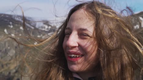 a joyful young woman stands at botev peak in stara planina, bulgaria. captured in slow motion, her hair blows in the wind as she smiles in the vast mountain setting