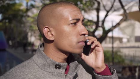 young man talking by smartphone and laughing outdoor