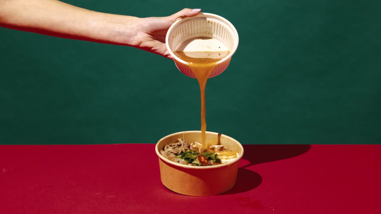 mujer vertiendo sopa sobre fideos en un cuenco