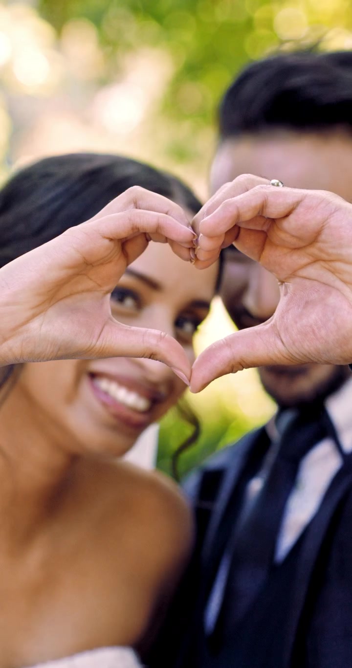 Feliz pareja de recién casados formando un corazón con las manos