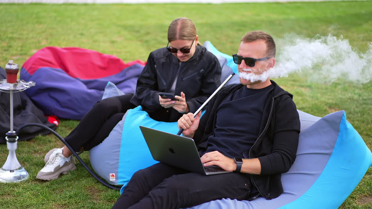 Couple Relaxing Outdoors with Hookah and Laptops