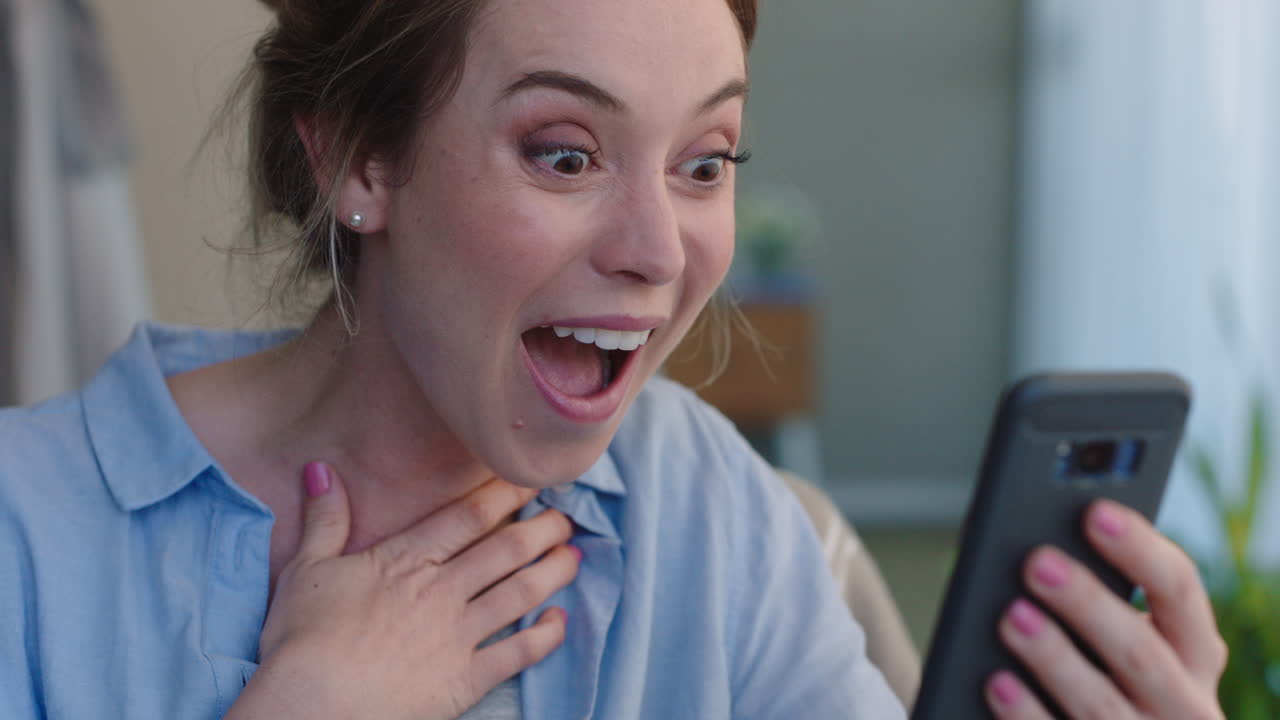 mujer hermosa que está chateando por video usando un teléfono inteligente hablando con un amigo pareciendo sorprendida disfrutando de la conversación en el teléfono móvil en casa