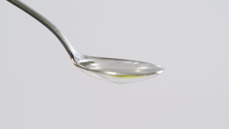 green olive falling on the spoon with olive oil