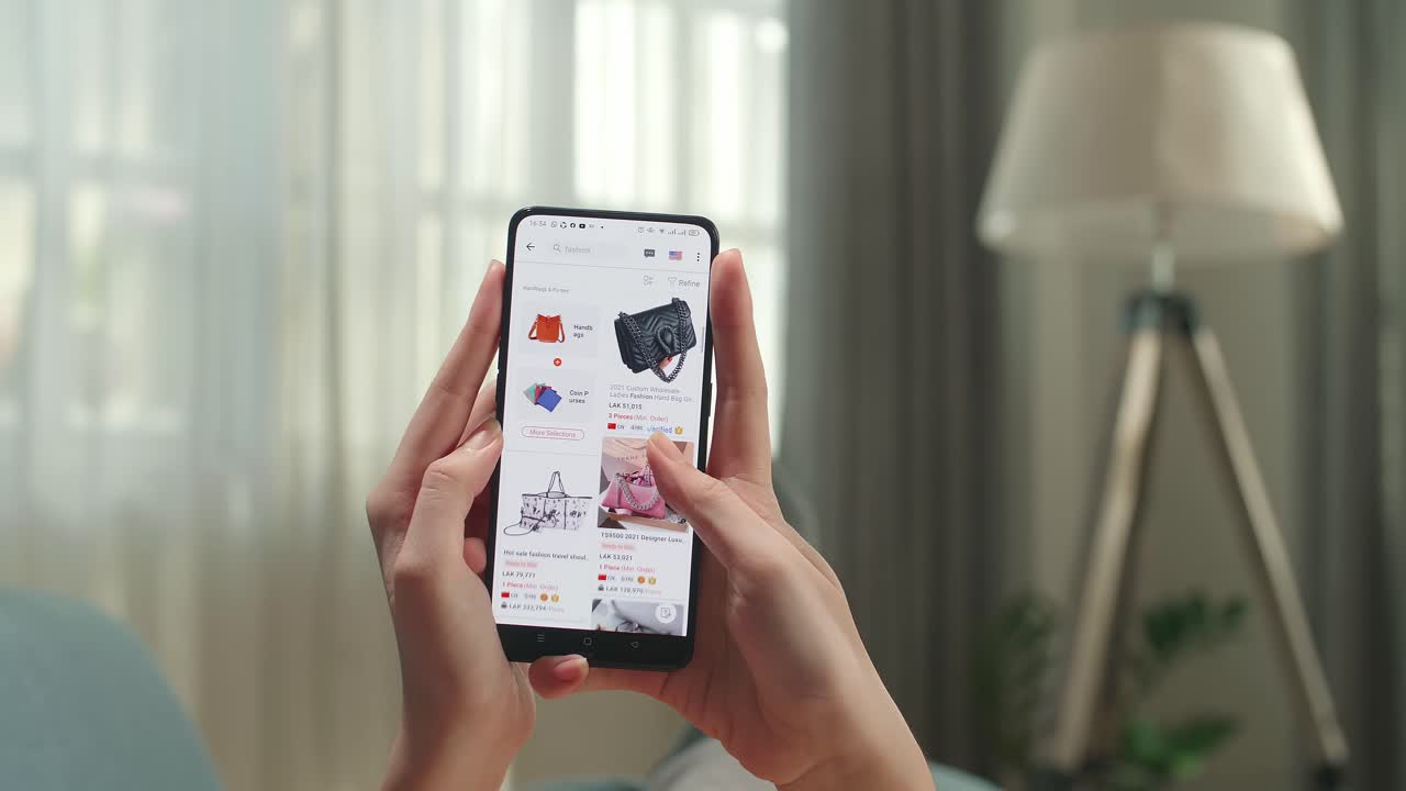 Close Up Of Hand Woman Lying On Couch In Living Room Using Smartphone Buys In Internet Shop. Female Looks At Goods In Online Store Bag. Buy Fashion Directly On Smartphone