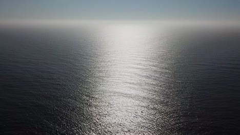 aerial shot of ocean in suns reflection