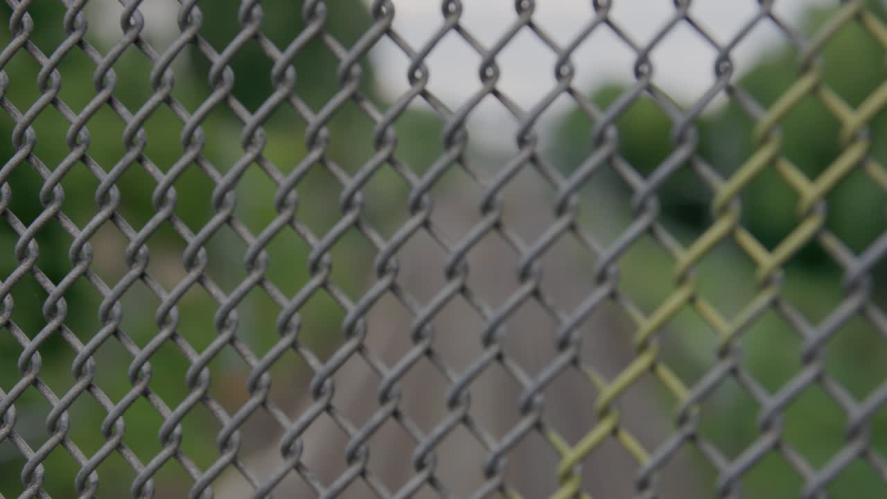 Long railway tracks surrounded by green foliage in Oslo with cinematic focus pull transitioning from sharp rails to blurred close-up of metal fence