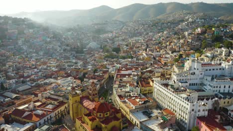 drone flies above guanajuato city center in mexico during daytime: catholic church, university buildings