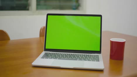 fotografía deslizante de una computadora portátil de pantalla verde de pie en el escritorio