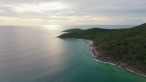 Wunderschönes-Sonnenaufgangslicht-Am-Morgen,-Das-Vom-Blauen-Ozean-Am-Hauptstrand-Von-Noosa-Reflektiert-Wird,-4K-Zeitlupendrohne,-Australien