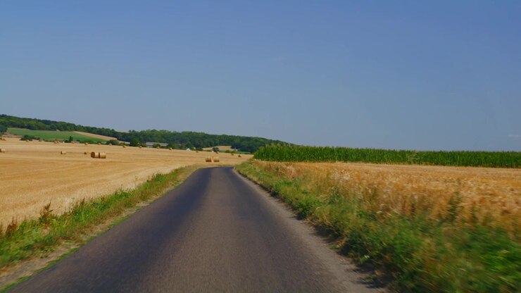 Ripresa in soggettiva alla guida su una strada tortuosa tra balle di fieno, campagna, area rurale, Francia, terreni agricoli, viaggio, parabrezza, estate, video HD, filmato stock, b-roll, esterno, ambientazione esterna, diurno, luce naturale