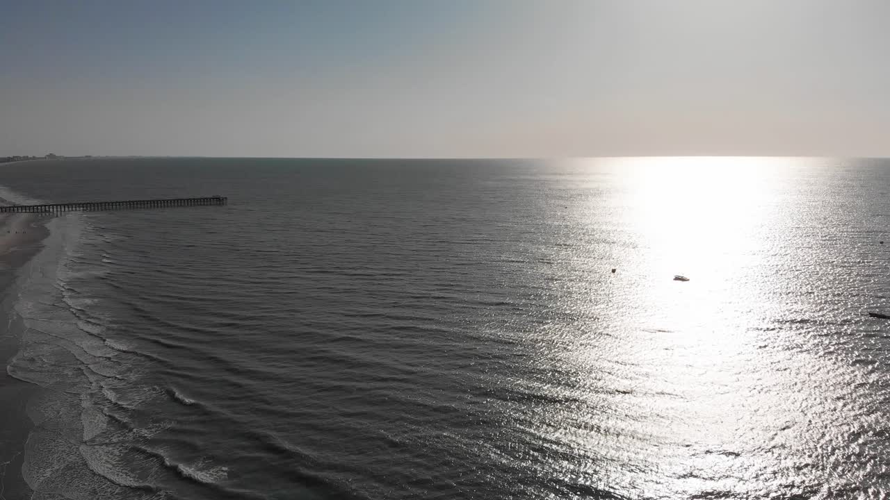 파도가 부드럽게 해안선을 때리면서 물 위의 바다에 지는 태양