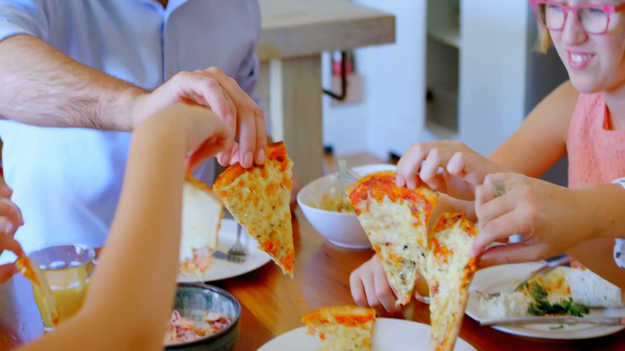 famiglia che mangia pizza in cucina 4k
