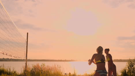 Gruppe-Junger-Mädchen,-Die-Bei-Sonnenuntergang-Oder-Sonnenaufgang-Beachvolleyball-Spielen