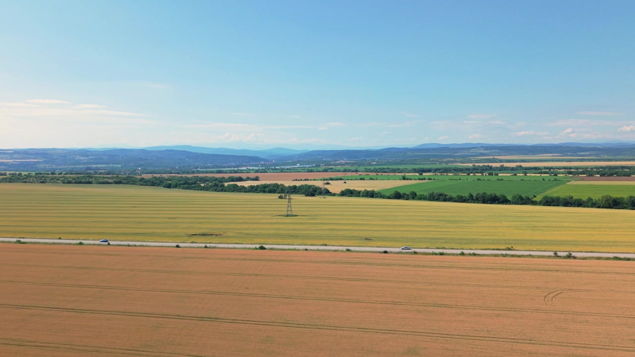 Cinematic aerial drone footage following a car driving along a peaceful rural road surrounded by lush agricultural fields and open countryside. Smooth tracking shot ideal for travel, transportation, r
