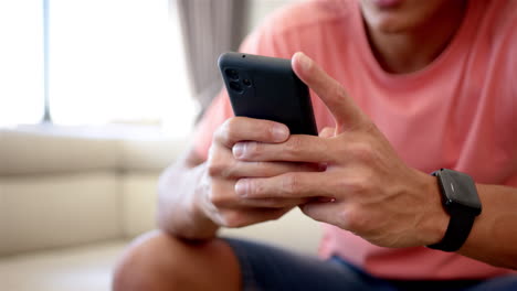 A-young-biracial-man-is-focused-on-his-smartphone