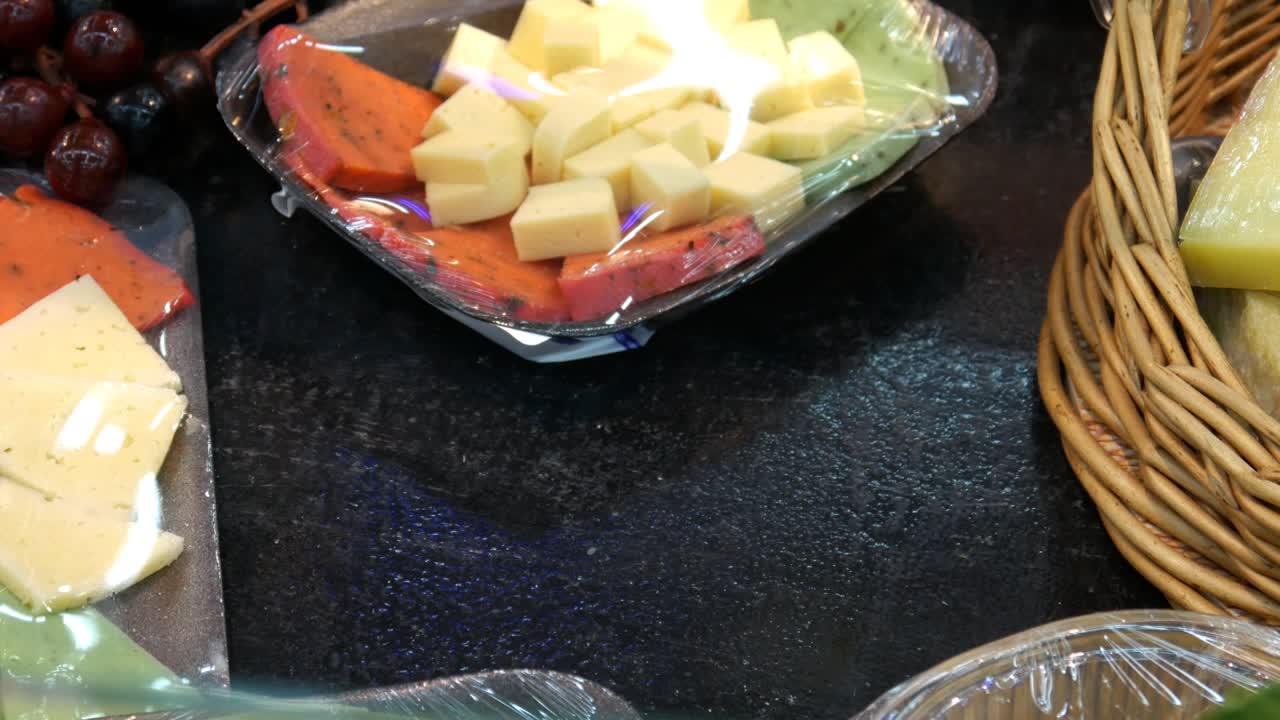 primer plano de un plato de queso envasado y la mano de un cliente masculino lo toma