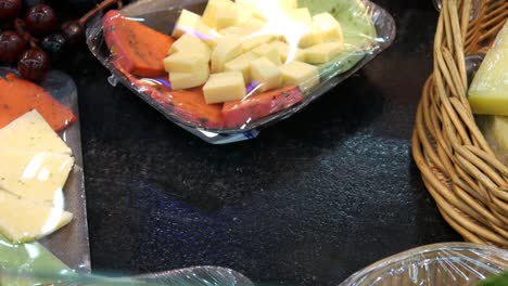 Close-up of packaged cheese platter and a male customer's hand takes it
