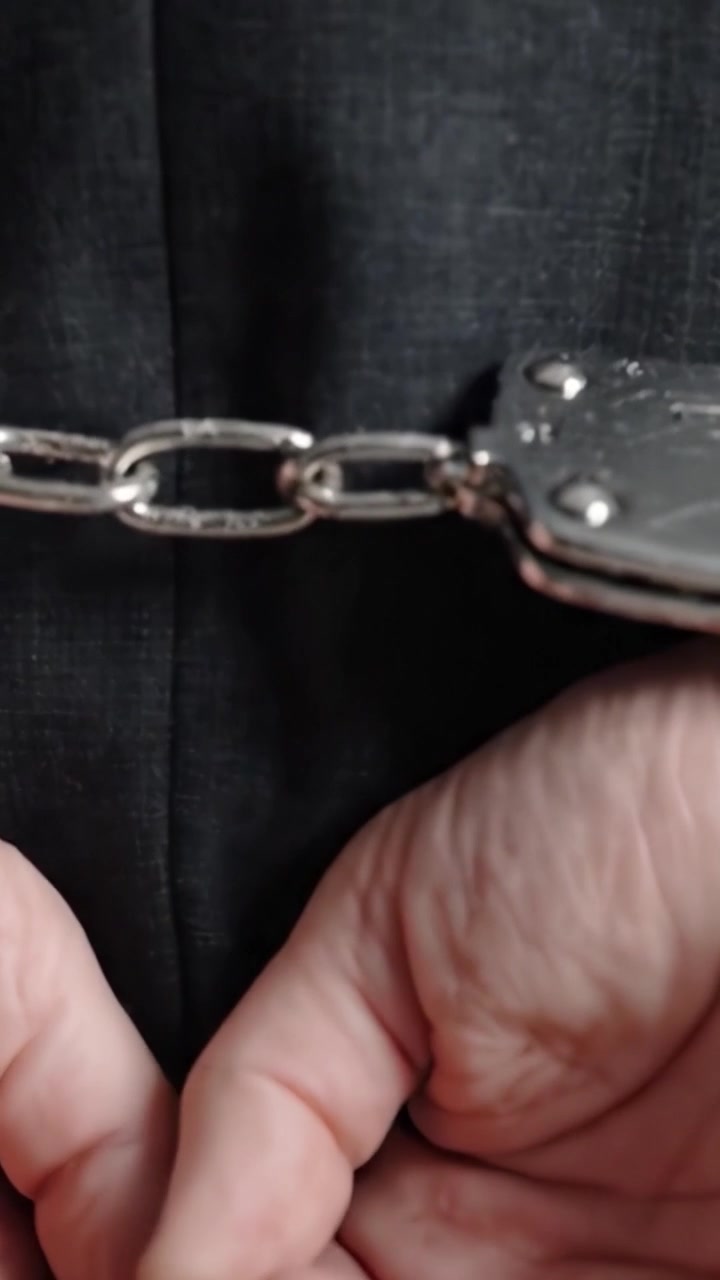 Un momento drammatico catturato: il peso emotivo delle manette che riflette una situazione seria in un ambiente dai toni scuri, evidenziando temi di prigionia e restrizione