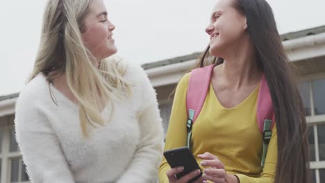 girls looking at the phone and laughing at high school