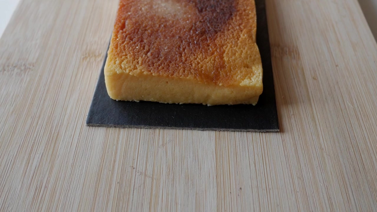 Blocco di Turron Yema su ardesia su tavolo di legno, delizioso dessert in primo piano.
