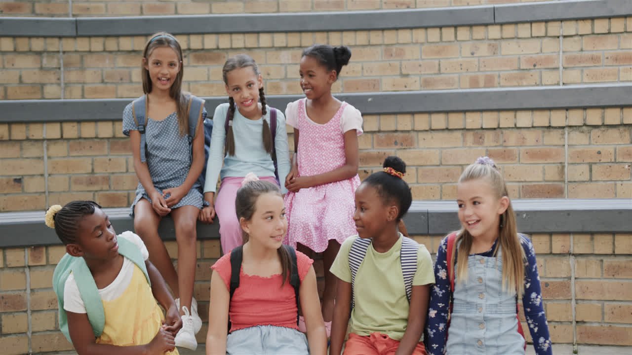 Portrait de joyeuses écolières diverses dans les escaliers, au ralenti, à l'école primaire
