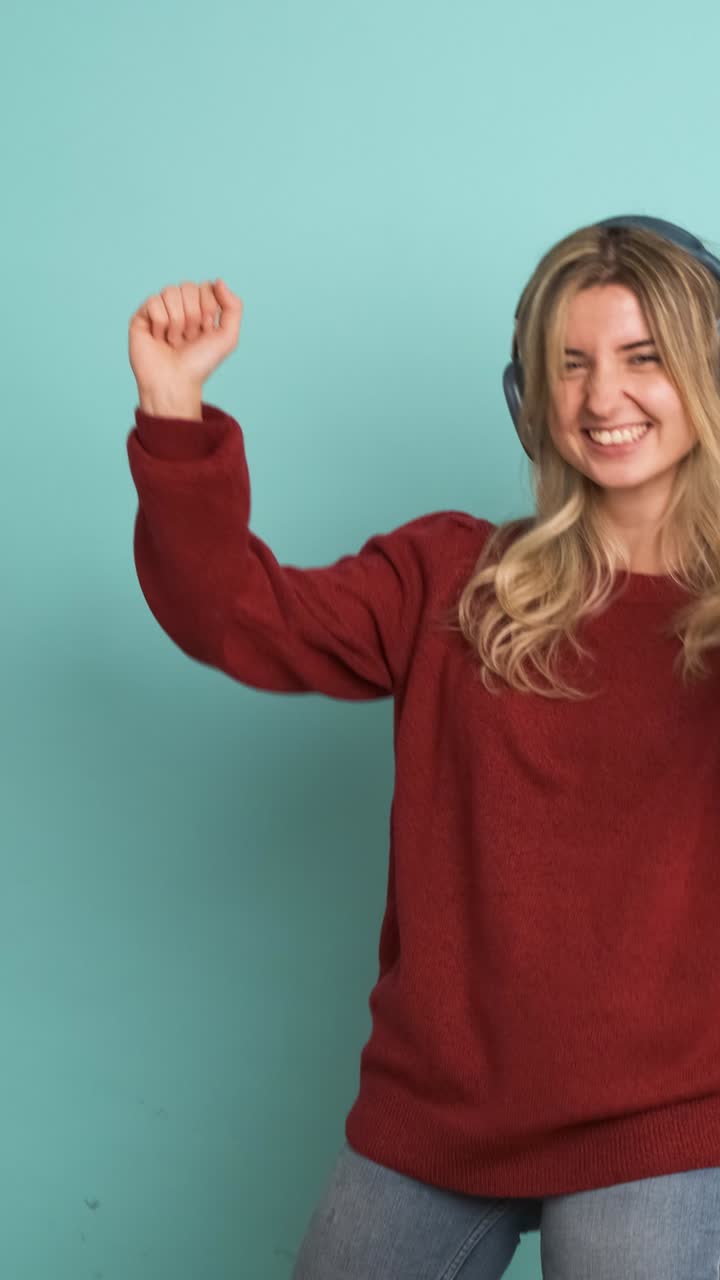 Excited woman dancing while listening to music using headphones