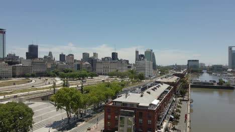 Restaurants-Am-Wasser-Am-Flussufer-In-Puerto-Madero-Mit-Der-Skyline-Von-Buenos-Aires-Im-Hintergrund-–-Drohnenabstieg