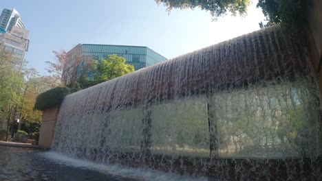 Caídas-De-Agua-Del-Paraíso-De-Hormigón-En-Perspectiva-Que-Bajan-De-Un-Edificio-De-Oficinas-Futurista-Con-Una-Piscina-De-Mármol-Poco-Profunda-Y-Un-Helecho-Sobre-El-Suelo-Colgando-Del-Borde-Con-Ventanas-Espejadas-Debajo-De-Las-Cataratas-1-4