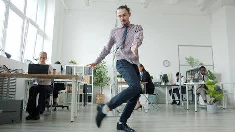 actor creativo realizando una danza en el trabajo mientras los hombres y las mujeres trabajan en las mesas