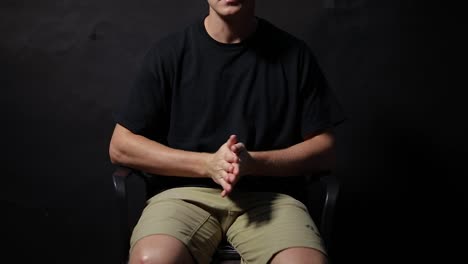 slow motion shot of a man sitting on a chair rubbing his hands together