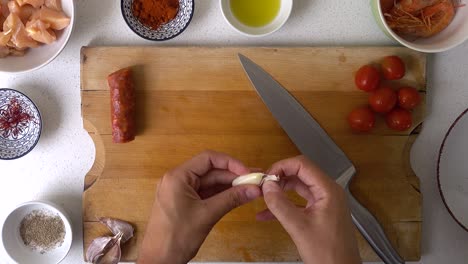 Looking-down-on-wooden-cutting-board-and-male-hands-peeling-garlic