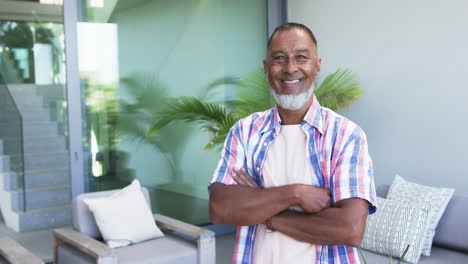 Un-Hombre-Birracial-Con-Una-Cálida-Sonrisa-Se-Para-Con-Confianza,-Con-Los-Brazos-Cruzados