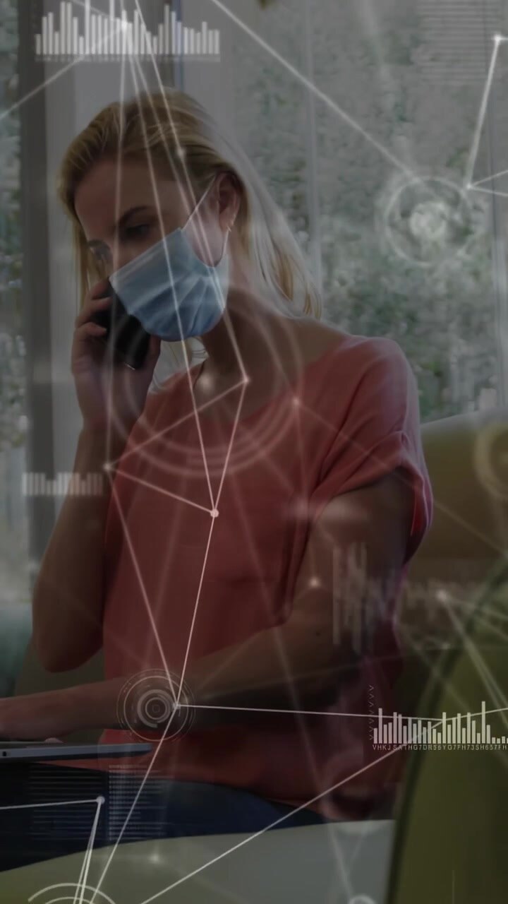 Vertical video: Woman taking call and tapping tablet in lounge, tech charts over screen aiding work