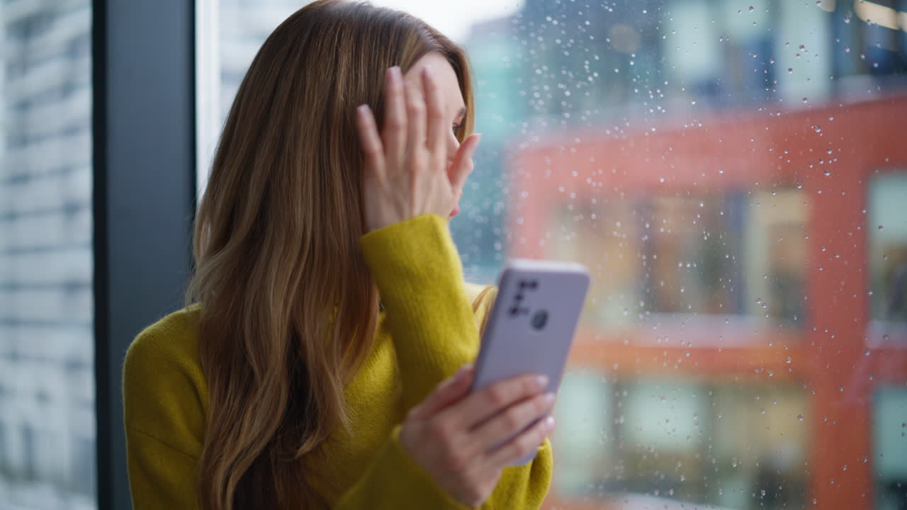 Thoughtful businesswoman holding mobile phone looking in window city closeup
