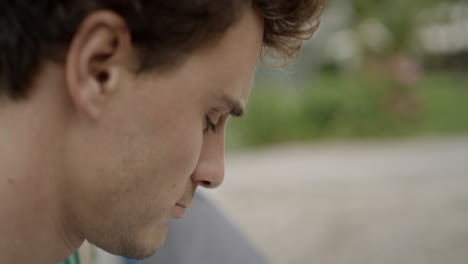 Close-up-of-a-young-man-reading-in-a-park