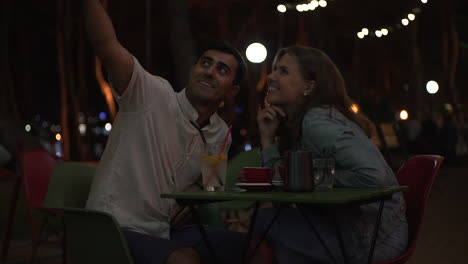 couple taking selfie at a night cafe