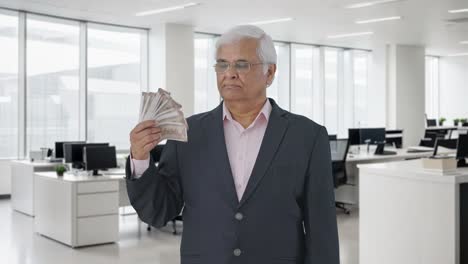 confident indian senior manager using money as fan