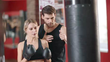 personal trainer training woman at boxing workout in sport club.