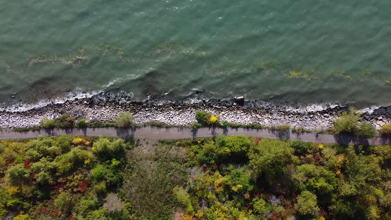 волны разбиваются о скалистый берег пляжа с прогулочной тропой на набережной