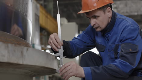 industrial worker inspecting a metal part with a measuring tool