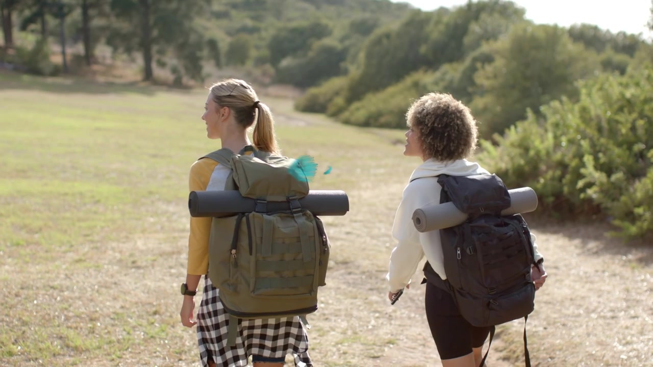 Two women hiking field as GOOD VIBES title appearing powder cloud obscuring hikers for branding