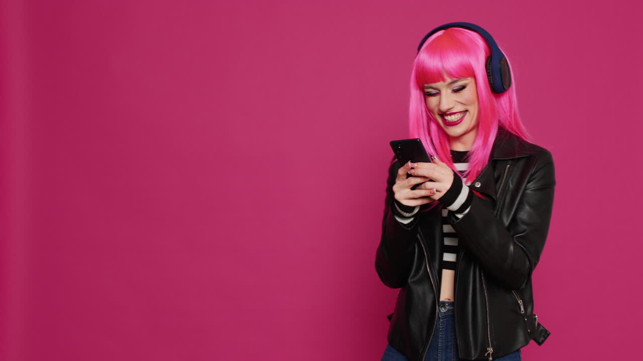 Young happy woman listening to music and texting on smartphone