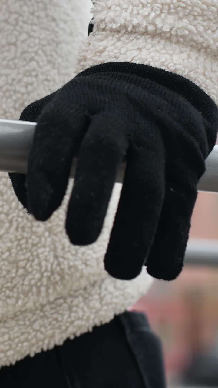 색 겨울 재과 검은 장갑을 입은 개인이 야외에서 푸시업을 수행하는 측면 뷰, 흐릿한 겨울 배경과 추운 날씨에 는 사람들의 불분명한 인물