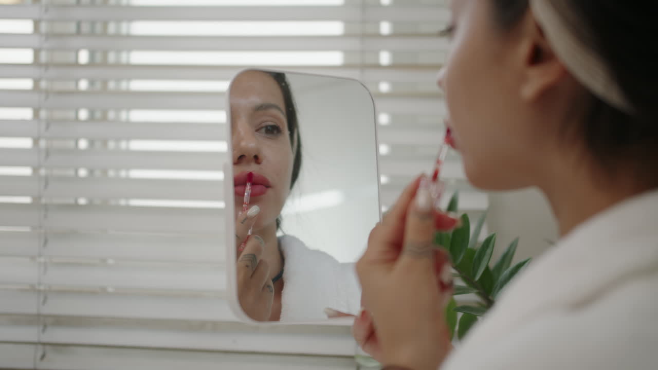 Woman Applying Red Lipstick on Lips in front of Mirror