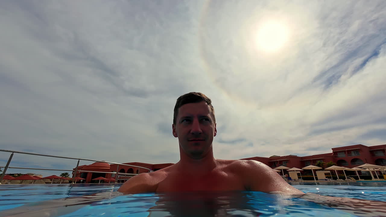 hombre adulto joven en una piscina fresca y refrescante - selfie de destino de viaje disparado