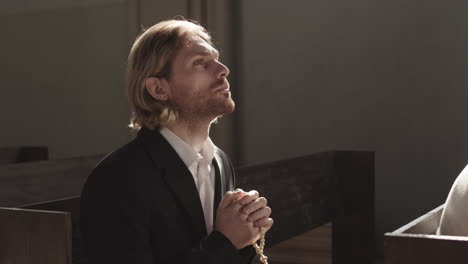 young caucasian man praying in christian church