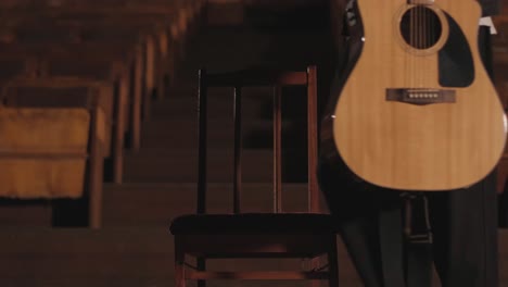 a handsome guy plays an acoustic guitar in an abandoned cinema. the musician sings a song and accompanies on the guitar