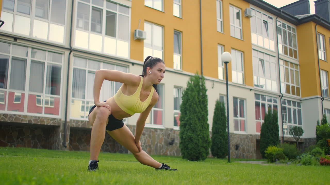 restaurando la fuerza después del entrenamiento. una mujer con auriculares se calienta antes de entrenar en el parque. estirándose al aire libre.