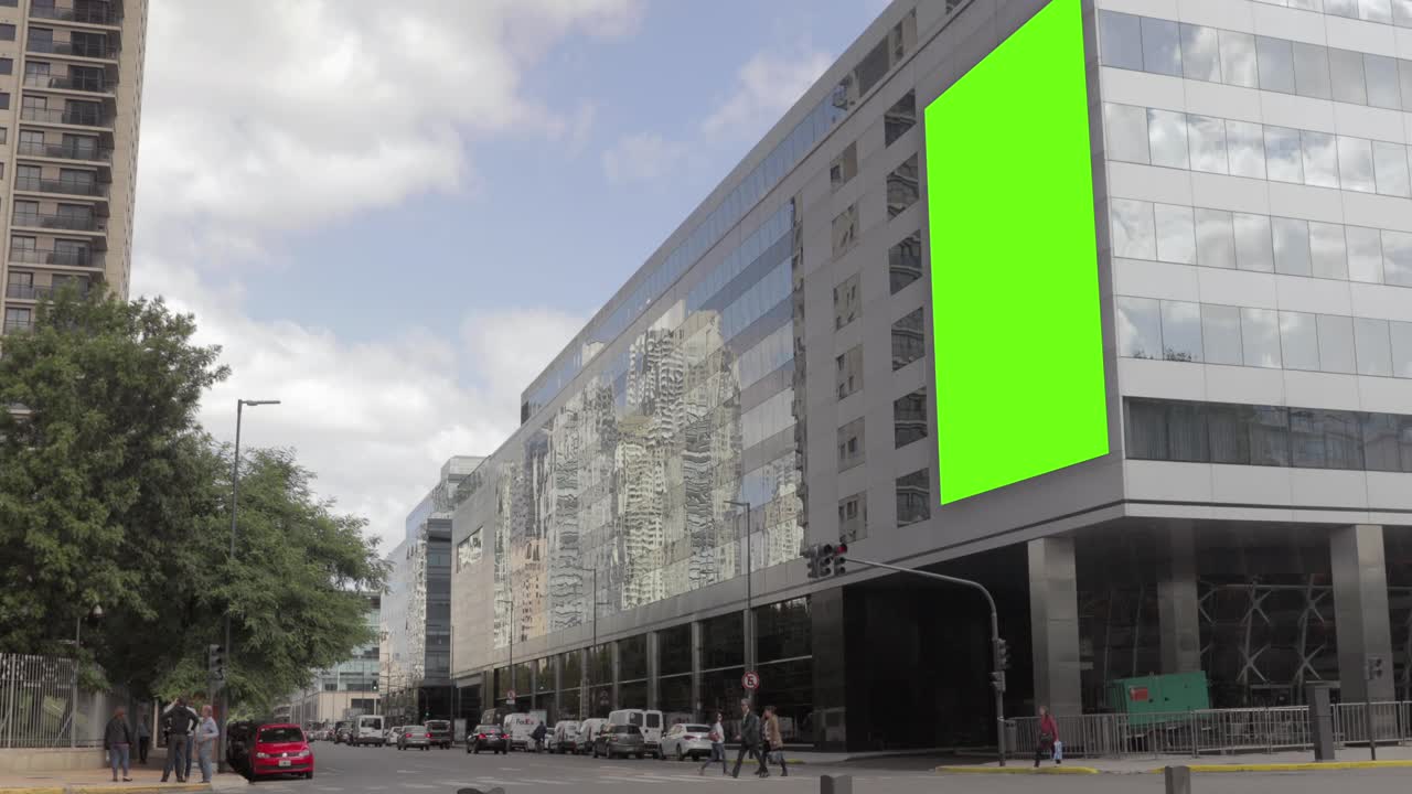 Edificio moderno in città con cartellone pubblicitario con schermo verde e traffico urbano