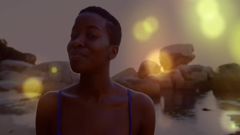 standing by rocky water, person surrounded by glowing lights in animation scene
